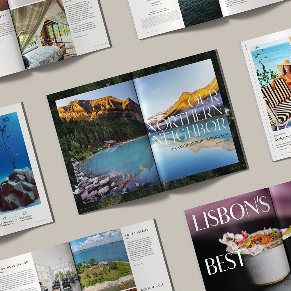 Numerous spreads of Inspirato Magazine lie open, showcasing lush travel and food photography overlaid with bold type.
